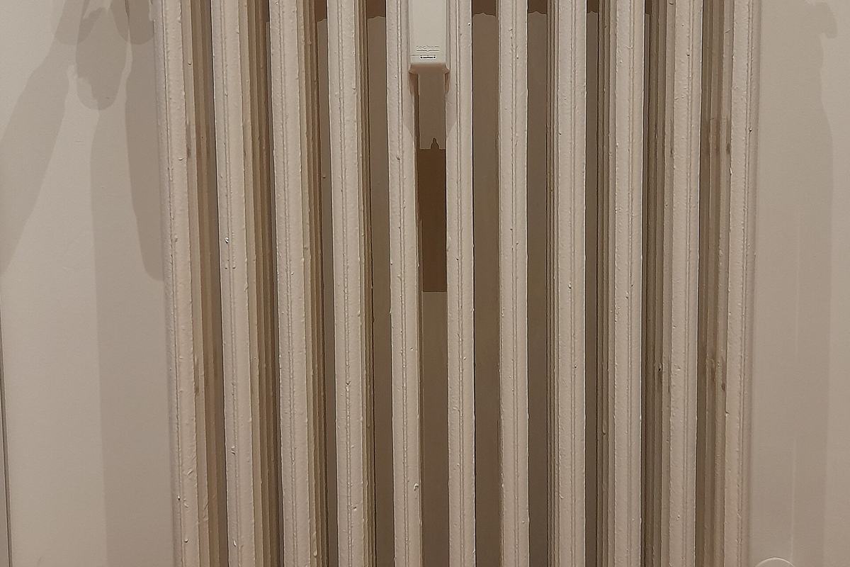 Radiador de calefacción blanco con válvula termostática junto a una pared