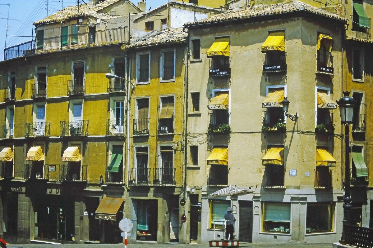 Fachadas de edificios de viviendas tradicionales con toldos amarillos en Toledo